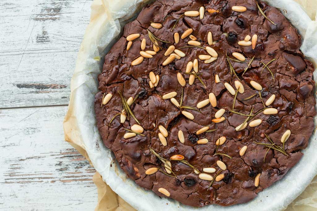 Castagnaccio, chestnuts, flour and olive oil, and decorated with pine nuts, raisins and rosemary. 