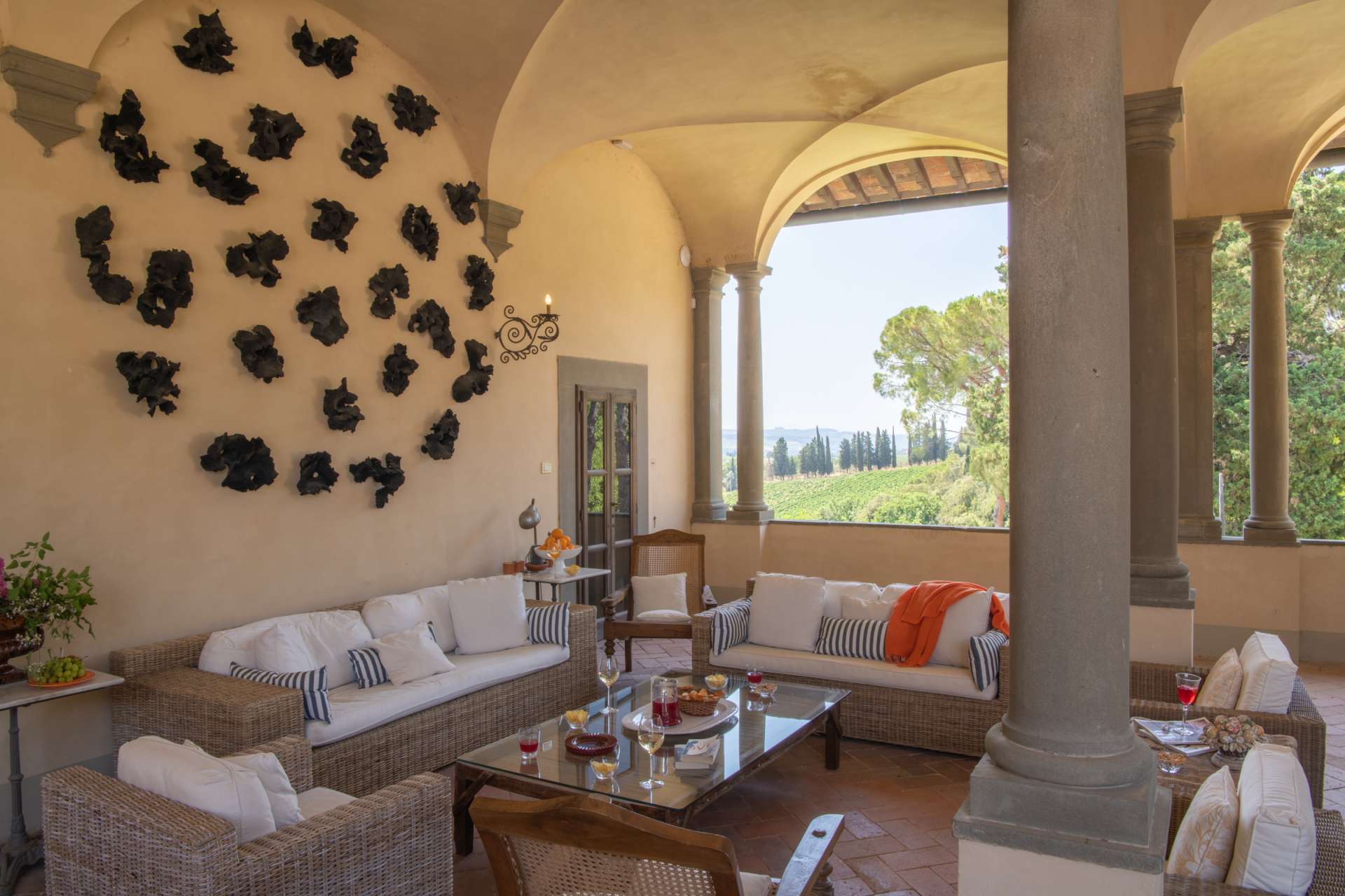 Luxury covered terrace at Villa Tinaccio in Tuscany Luxury covered terrace at Villa Tinaccio in Tuscany with elegant outdoor lounge area, stone columns, and panoramic countryside views