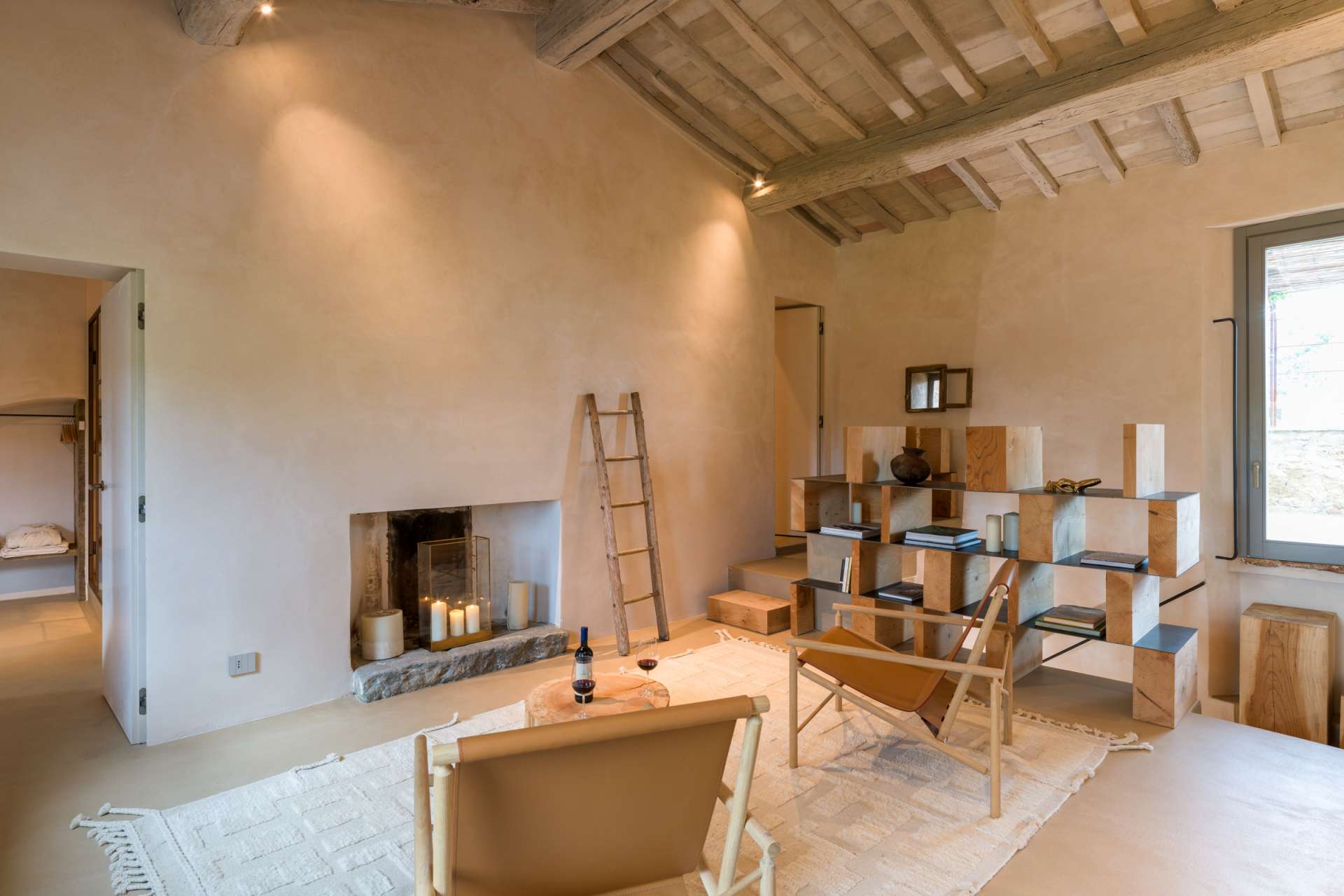 Luxury living room at Pieve di Ponsano villa in Tuscany Luxury living room at Pieve di Ponsano villa in Tuscany featuring a minimalist interior, wooden beam ceiling, fireplace, and elegant contemporary furnishings
