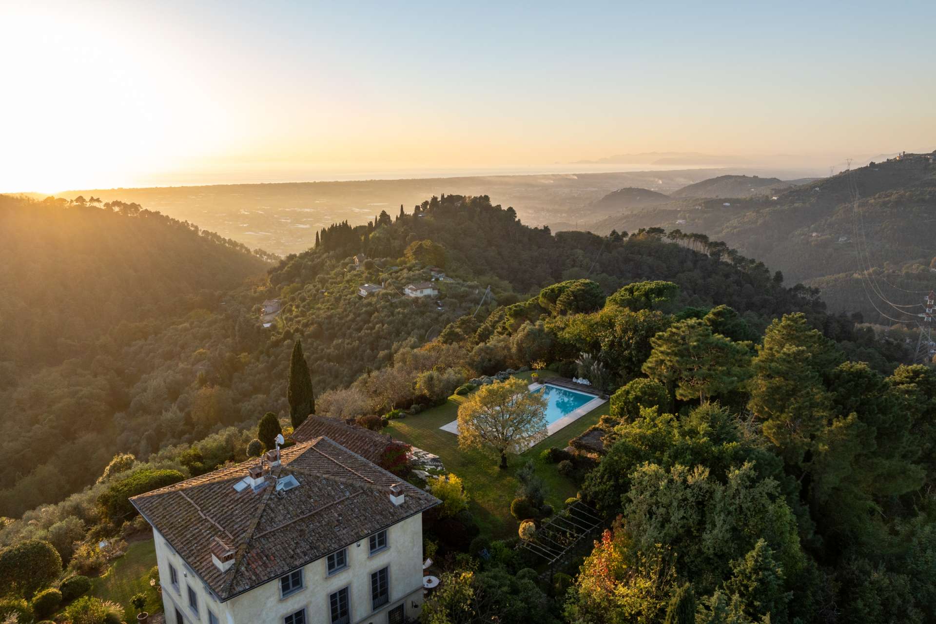 Sunset aerial view of Villa Cieli in Tuscany with private pool, gardens and panoramic hillside landscape.