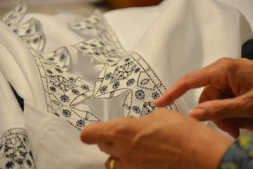 The Artisans of Florence - Women showing a piece of clothing to a visitor of the workshop in Tuscany