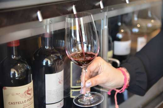 Chianti Wine Tour - A glass of red wine is poured in front of a selection of wine bottles.