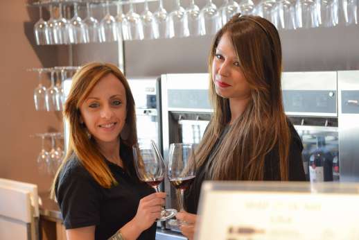 Chianti Wine Tour - Two women behind the bar sample glasses of red wine.