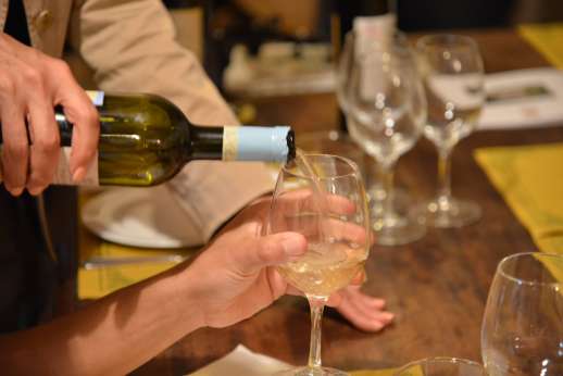 Fiat 500 Tour - White wine from a bottle is poured into a wine glass at a wooded table