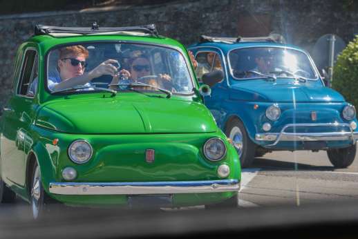 Fiat 500 Tour - Two classic Fiat 500s sit in the sun, as the driver of the blue Fiat climbs out of his car.