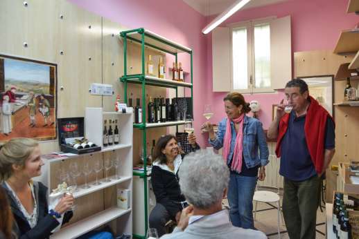 Lucca By Bike Or Foot - A tour group enjoy a wine tasting in a room with pink walls and paintings
