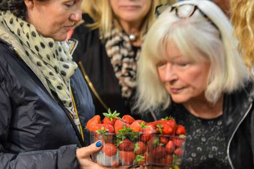 Florence Market Tour - A group of women inspects a plastic box of strawberries