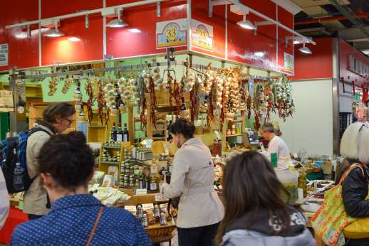 Florence Market Tour - Shoppers crowd around an Italian stall with hanging garlic.