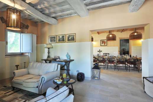 Il Borgo di Petroio - Large sitting room with TV area and fireplace leading into the dining room on the ground floor of the main house.