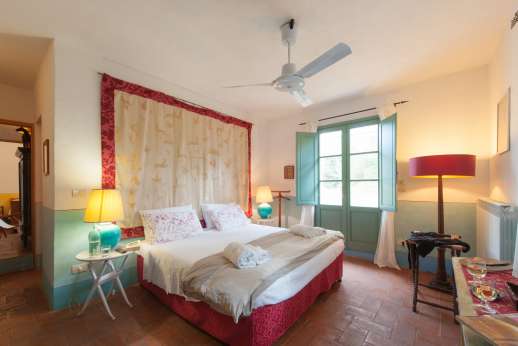 La Magione - Double bedroom with an en suite bathroom with bath and glass doors opening to the garden facing the swimming pool.