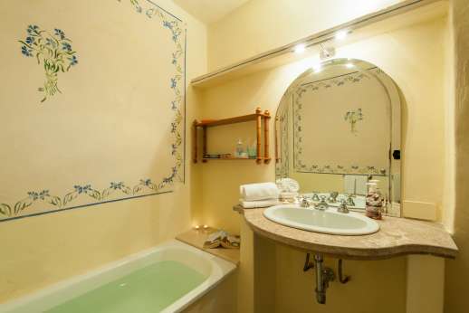Tizzano - Hand-painted decorations in bathroom with bath and hand-held shower.