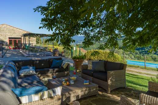 Il Borgo di Petroio - Open air living area with comfortable sofa shaded by a large chestnut tree.