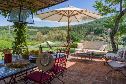 La Sobole- Yellow Wing - glass doors opening onto a wide furnished dining loggia that looks onto the olive and cypress trees on the opposite hillside