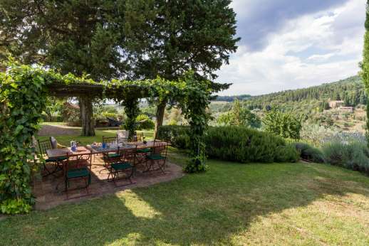 La Sobole - Orange Guest House rear garden furnished with tile-covered tables and seating area underneath a vine-covered pergola