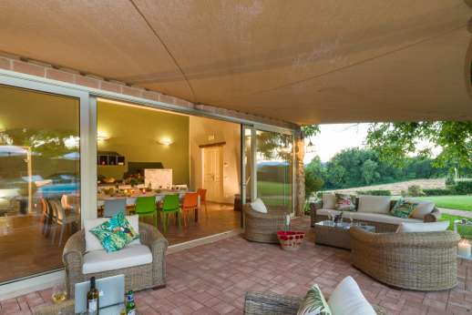 Solomonio - A shaded and spacious outdoor sitting area fitted with comfortable sofas and armchairs in front in front of the veranda facing the pool