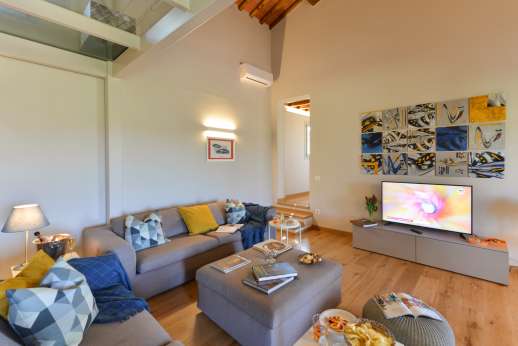Maggiano Piccolo - Ground floor living room furnished with two large sofas, tv, and connected through a flight of stairs to a mezzanine floor