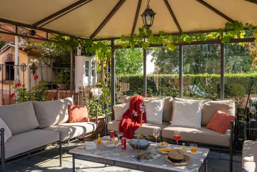 Rosso Fiorentino - The shaded sitting area under a white canvas pergola.