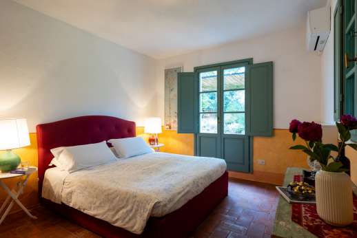 La Magione - Double bedroom with an en suite bathroom with bath and glass doors opening to the garden facing the swimming pool.