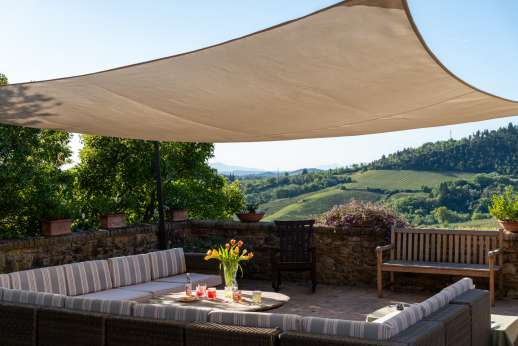 Podere Celli - The large paved terrace with seating area and loggia by dusk